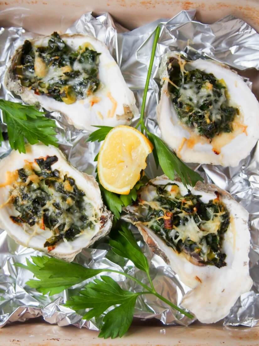 Oysters Rockefeller in dish from overhead with slice of lemon in middle