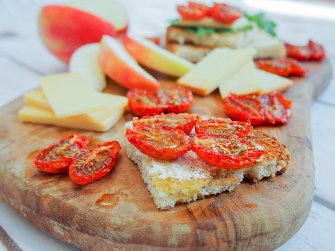 slow roasted tomatoes on piece of toast with more to side plus cheese and apple slices
