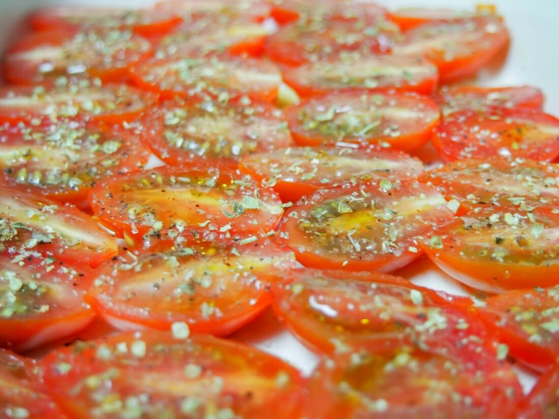 tomatoes topped with oil and herbs ready to put in oven