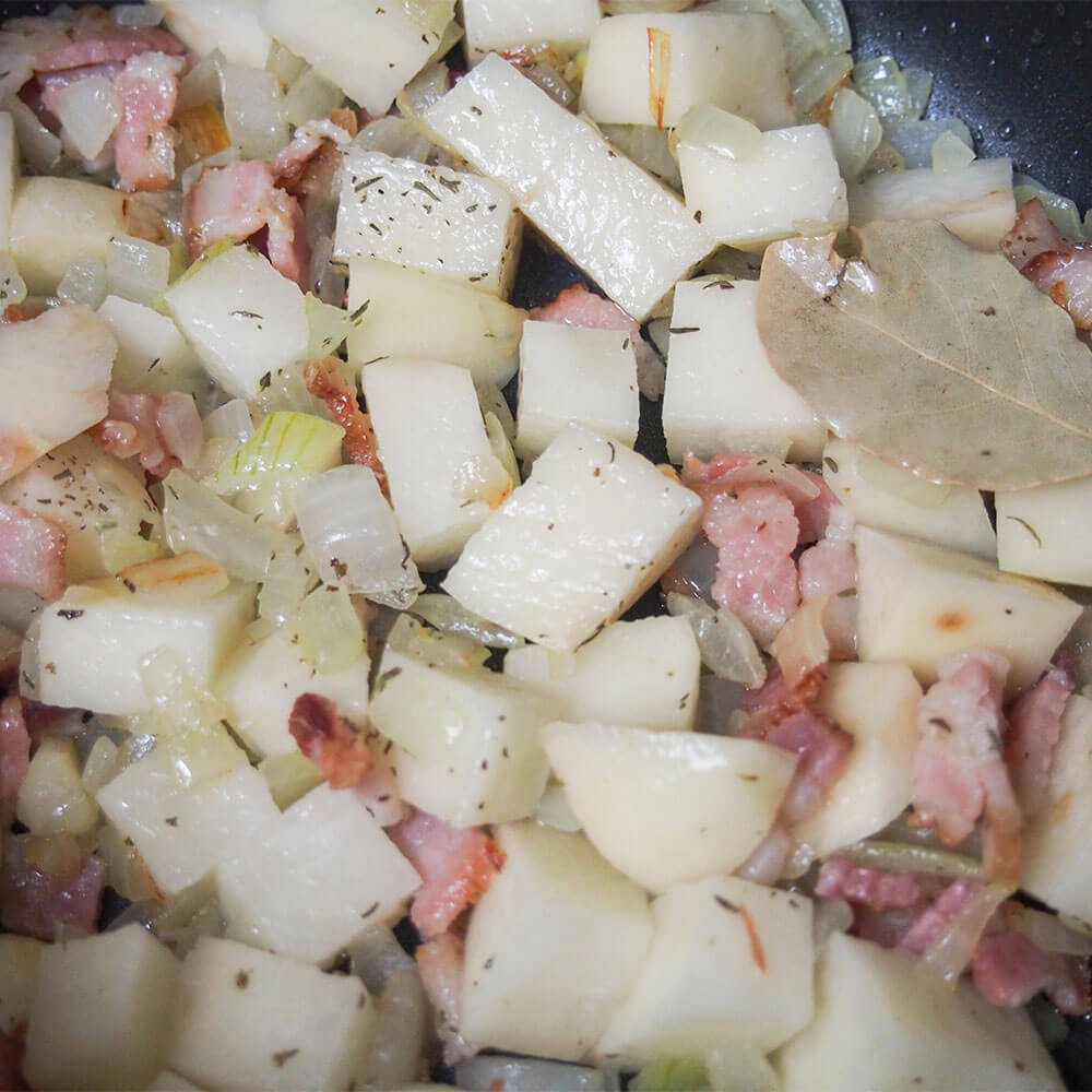 bacon, onion and potatoes cooking with herbs as base of soup