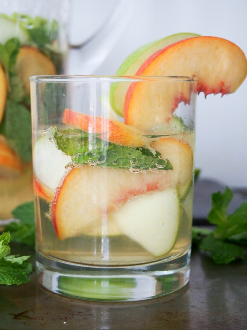 white sangria with whiskey, apple and peach - Gently sweet, fruity and with a lovely freshness from the mint, this white sangria is elegant and perfect for parties. IT'll become your go-to drink all summer! Also perfect colors for a less cliched St Patrick's Day cocktail. 