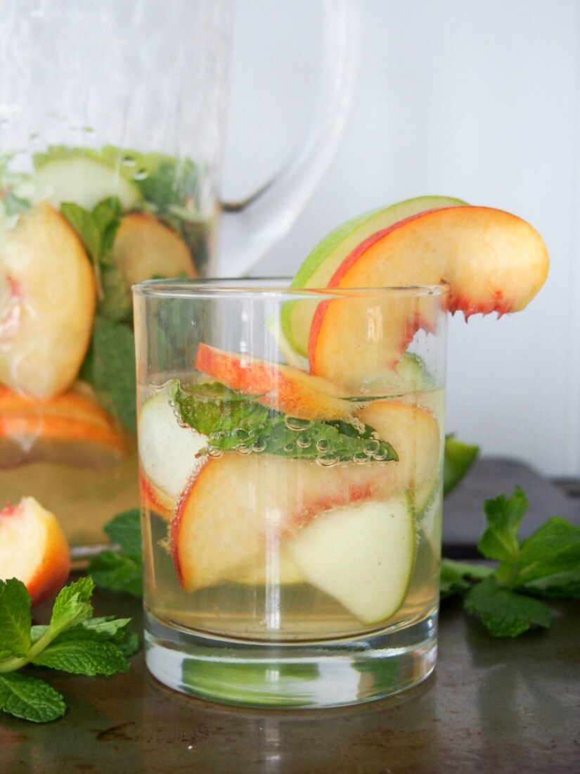 white sangria with whiskey, apple and peach - Gently sweet, fruity and with a lovely freshness from the mint, this white sangria is elegant and perfect for parties. IT'll become your go-to drink all summer! Also perfect colors for a less cliched St Patrick's Day cocktail. 