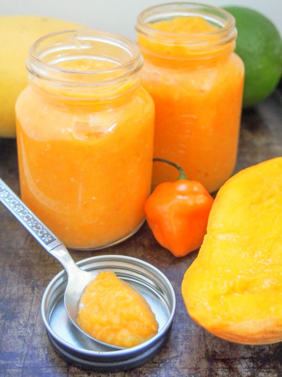 Mango habanero sauce gives a wonderful sweet-spicy kick to tacos and more. Really easy to make, and surprisingly healthy, it'll be a go-to hot sauce. two jars of mango habanero sauce with spoonful resting in front