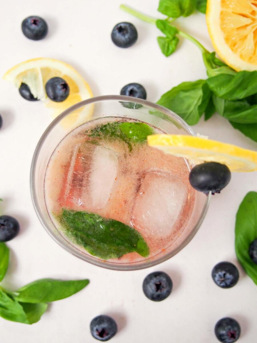 This bashful blueberry cocktail is a delicious mix of blueberries, lemon, vermouth, whiskey and a hint of basil. Topped with soda, it's a refreshing drink. Easy to make & enjoy!