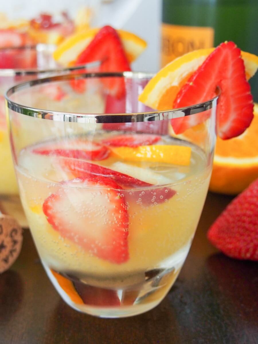 Sangria is a summer classic, but cava sangria is that bit more special. Light, refreshing and a wonderful mix of fruit and cava's bubbles. Quick to make, it's an easy cocktail perfect for any occasion from summer BBQs to holiday parties. glass of cava sangria viewed from side with bottle behind
