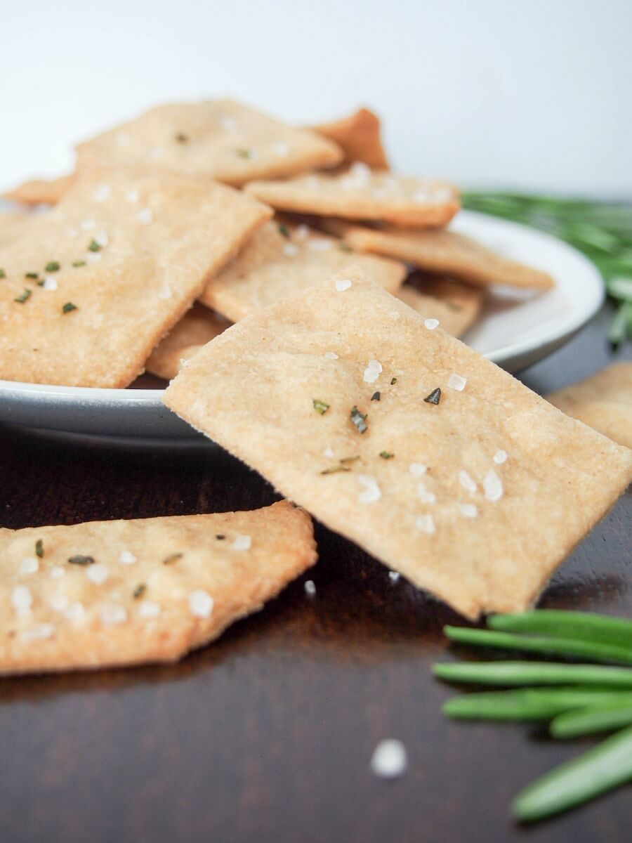 whole wheat olive oil crackers on plate with one resting on edge
