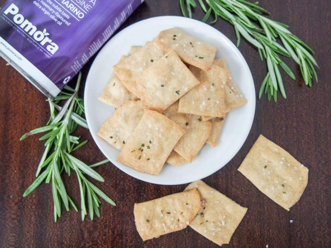 whole wheat olive oil crackers on plate from overhead with rosemary sprigs to side