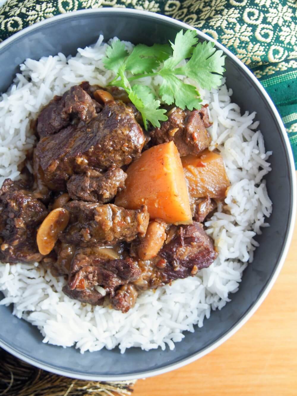 Beef massaman curry in bowl over rice from above with cilantro garnish