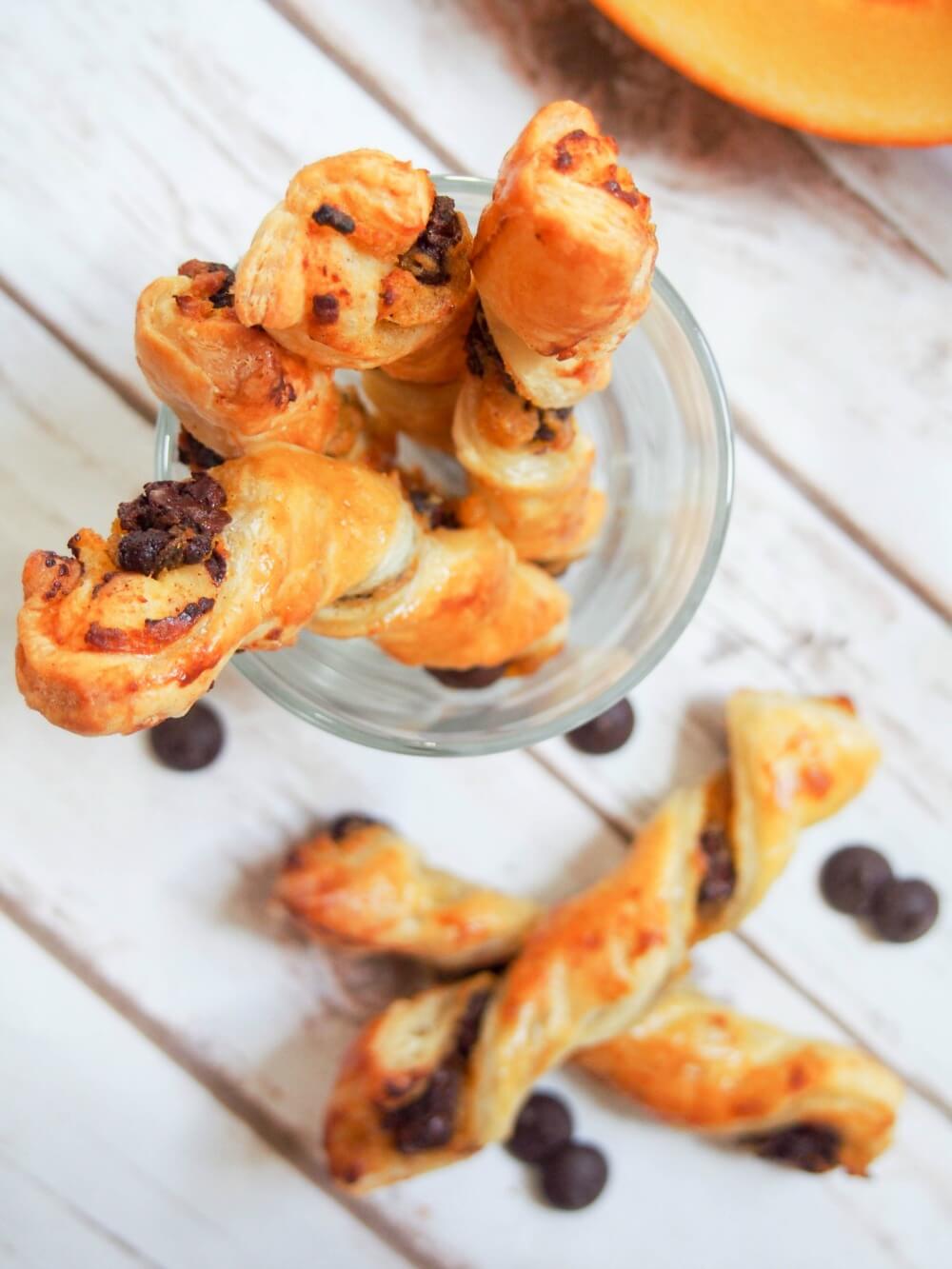 Whether you're a pumpkin fan or not, these chocolate pumpkin pastry twists are sure to be a hit. A deliciously simple combination with a bit of sweet, a bit of spice, crisp pastry and soft filling. Chocolate pumpkin pastry twists in glass from overhead