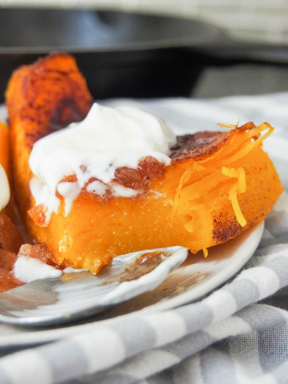 close up of piece of kaddo bowrani (Afghan pumpkin with yoghurt sauce) with spoonful taken from chunk and spoon in front