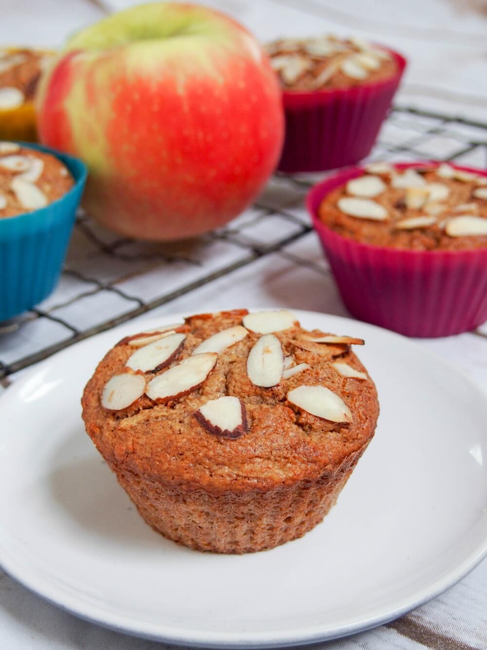 apple muffin on plate in front of others and apple behind