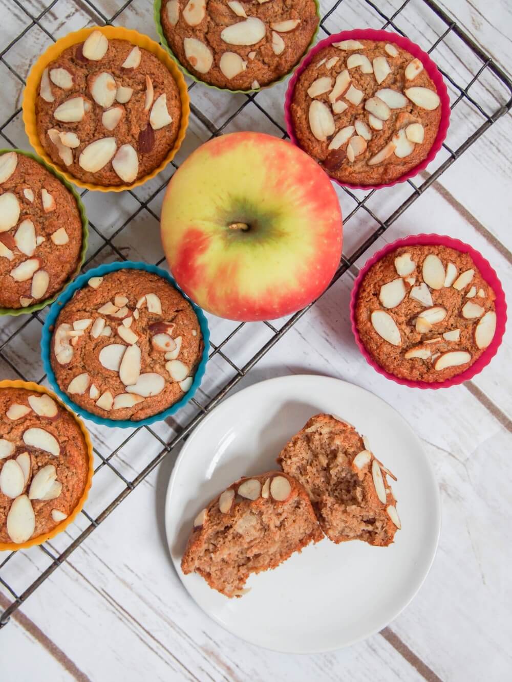 apple muffins on cooling rack with one split open on a plate from overhead