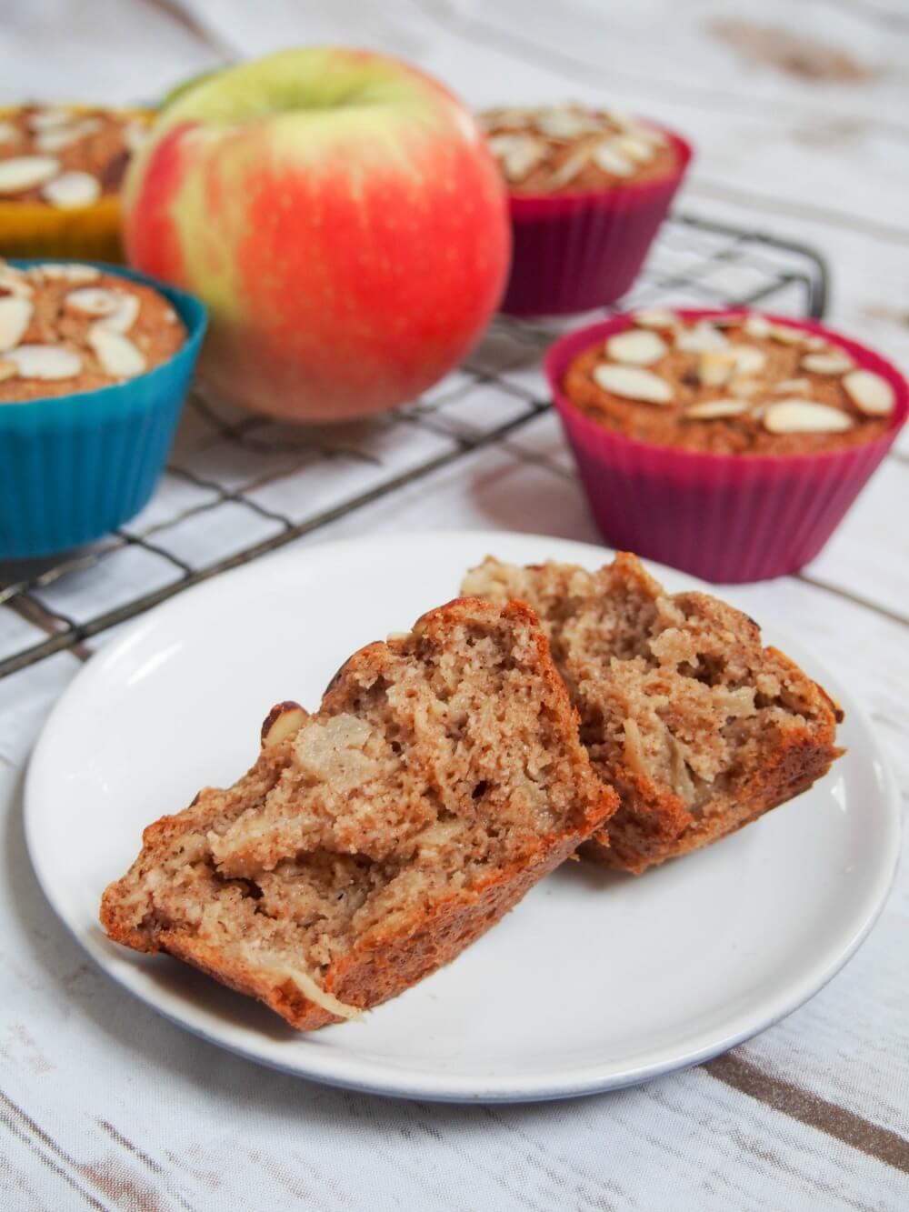 split open apple muffin in front of others on cooling rack