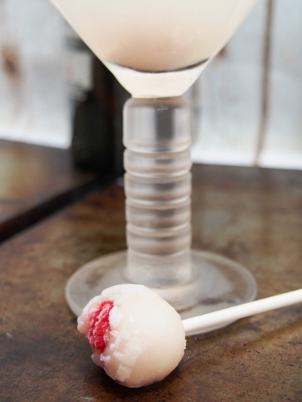 lychee raspberry 'eyeball' stirrer below glass of lychee martini