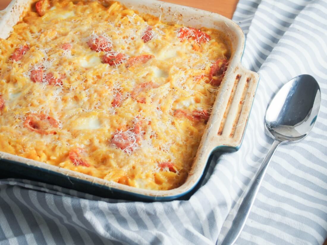 This cheesy orzo pasta bake is comfort food on a plate, with a slightly healthy twist. With lots of cheese and veggies, it's a great vegetarian meal. Cheesy orzo pasta bake in baking dish with spoon to side