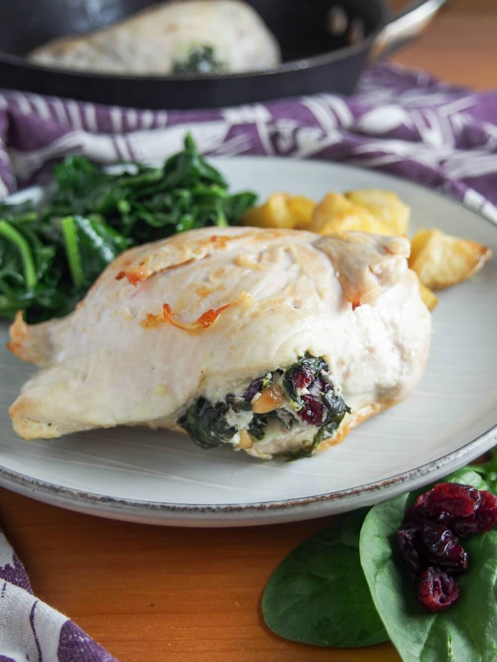 whole stuffed chicken breast on plate with sides behind