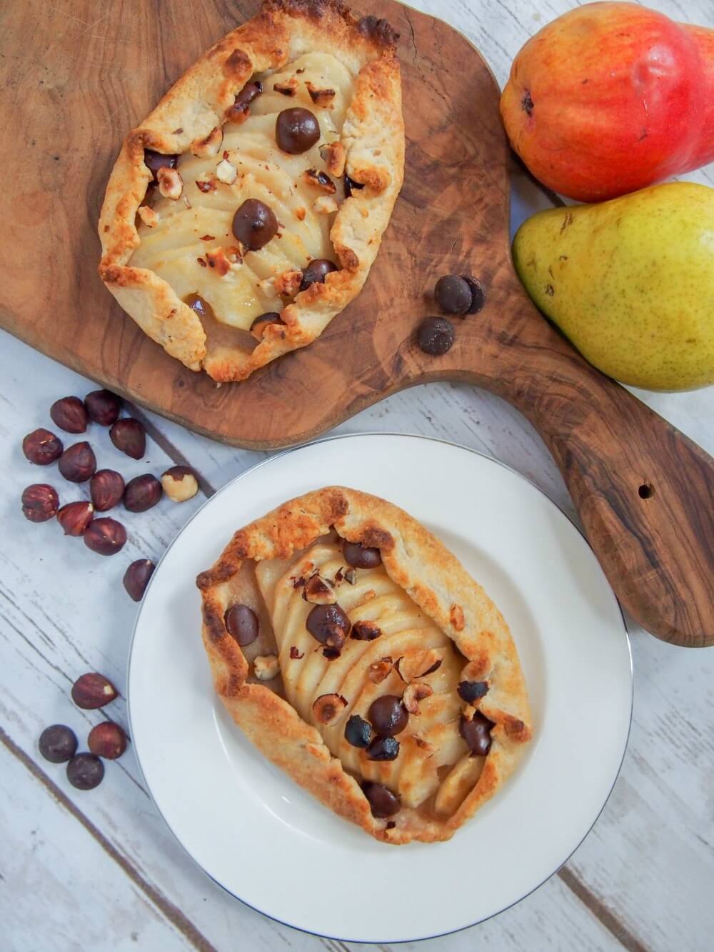 Individual pear galettes from overhead with pear, hazelnuts and chocolate chips to side