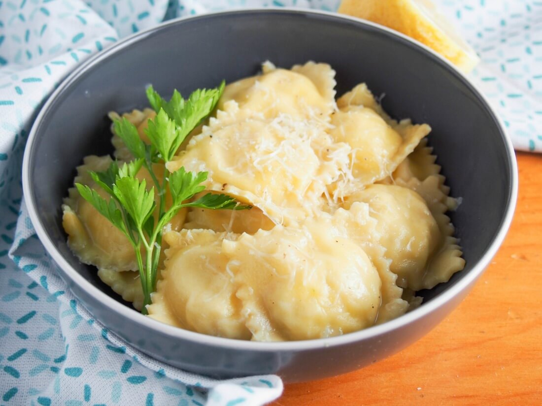 crab ravioli in bowl with parsley on side of bowl