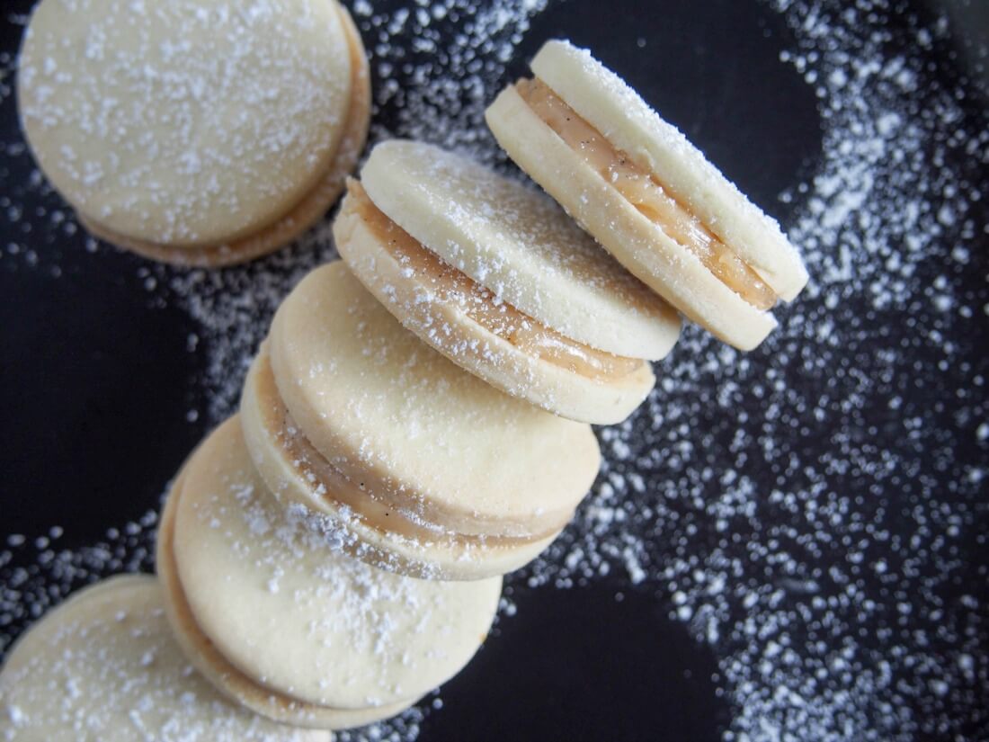 Alfajores - dulce de leche sandwich cookies resting against each other showing filling inside