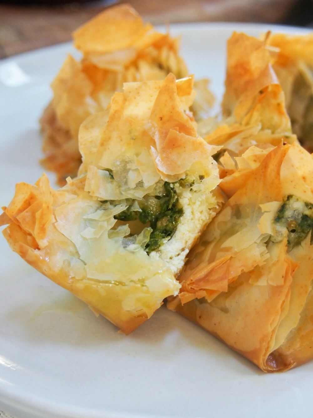 Pesto goats cheese filo parcel split open showing filling, resting on another