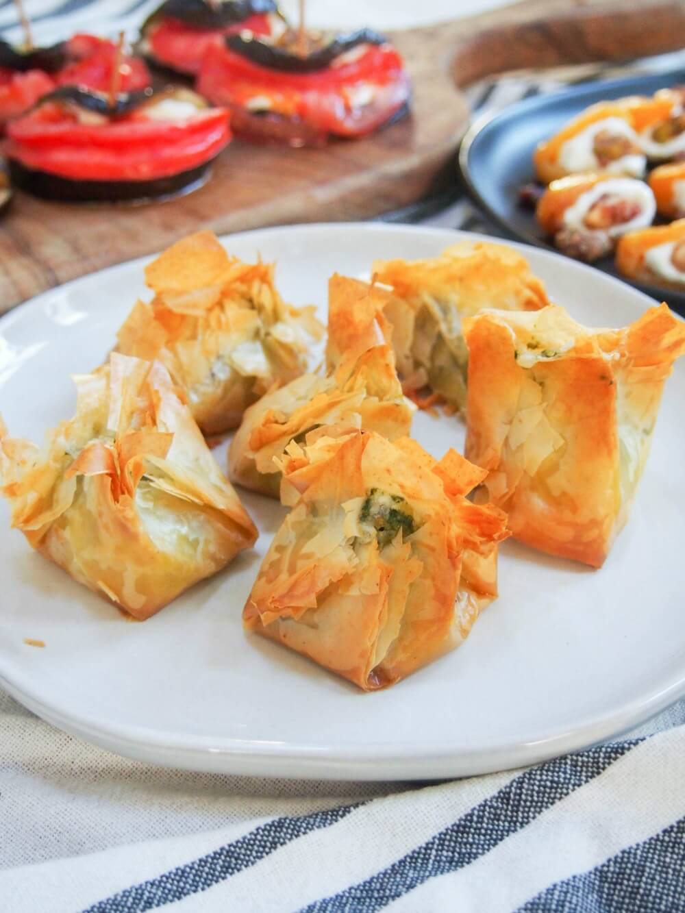 Pesto goats cheese filo parcels on plate with other appetizers behind