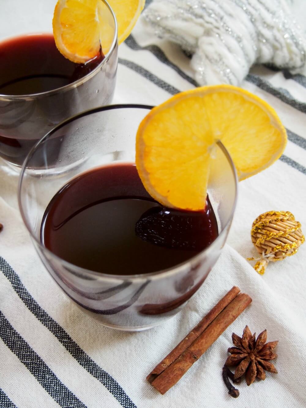 glasses of gluhwein garnished with a slice of lemon with spices to side of glass