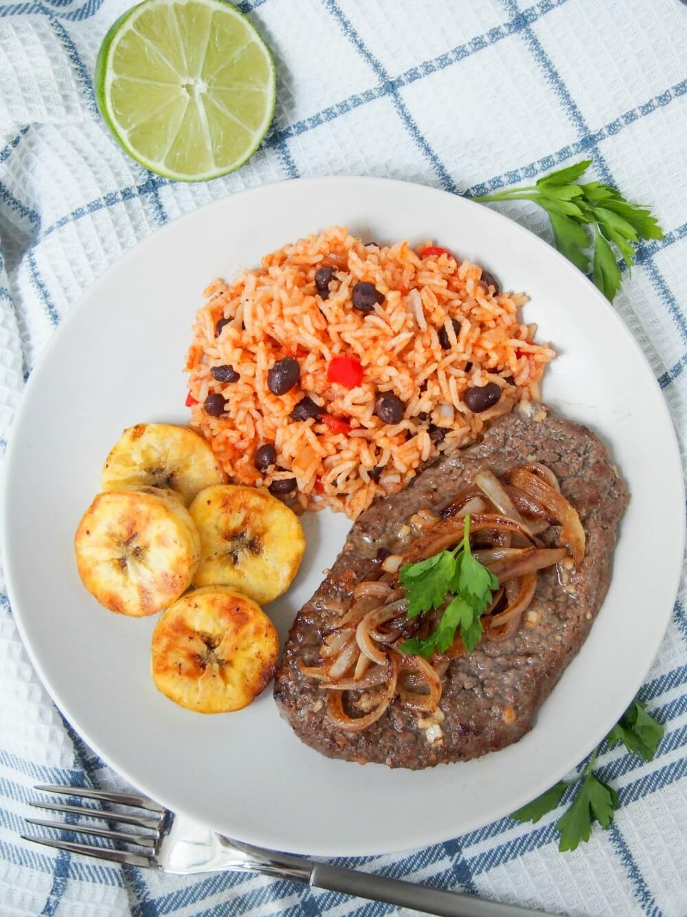Cuban cube steak - bistec de Palomilla  - on plate with plantains and beans and rice from overhead