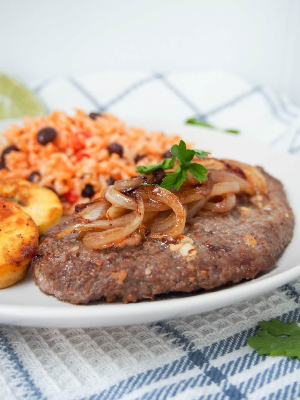 Cuban cube steak - bistec de Palomilla topped with onions with rice behind
