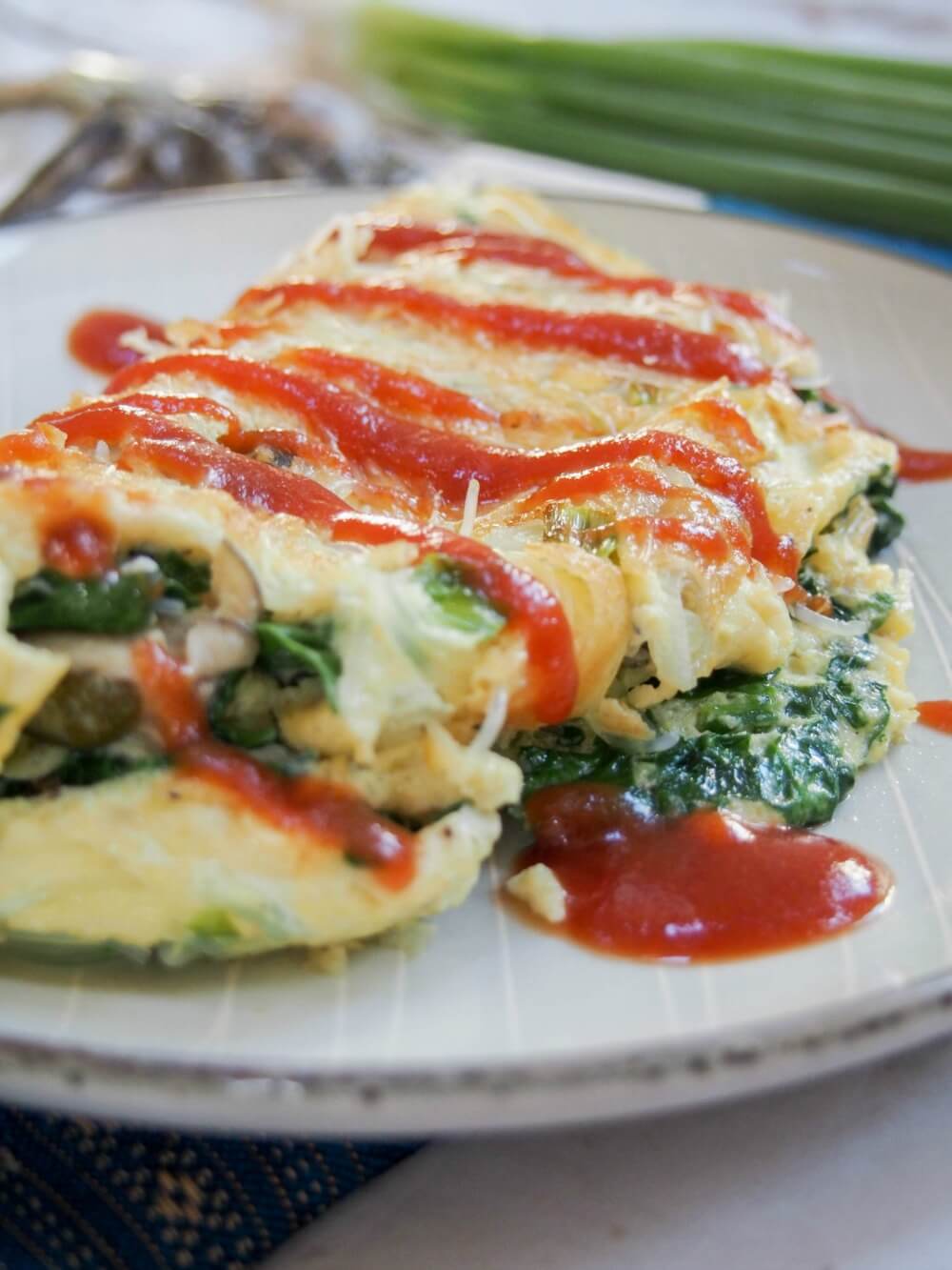 Taiwanese oyster omelette is a classic street food, but it also makes a delicious brunch/lunch - easy to make and with lots of great flavor, with oysters, greens and a flavorful sauce. close side view of Taiwanese oyster omelette with sauce over top