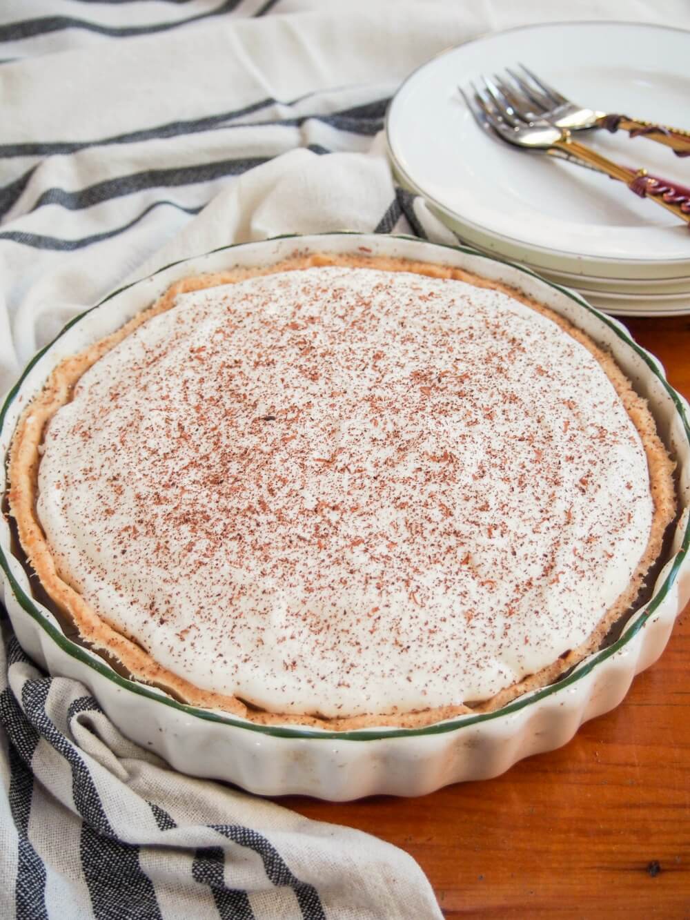 whole banoffee pie in dish with small plates and forks behind