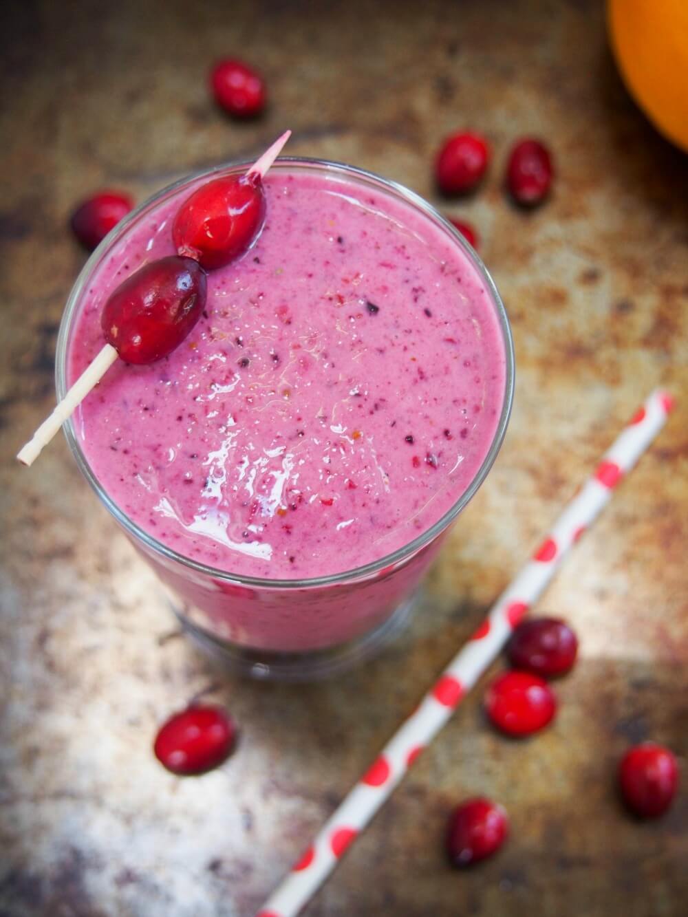 cranberry smoothie viewed from overhead topped with cranberries on cocktail stick garnish