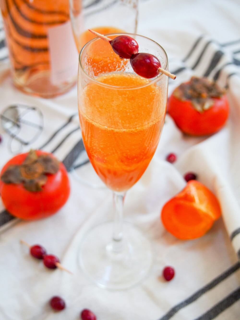 glass of persimmon apple cider mimosa with persimmons to side of glass