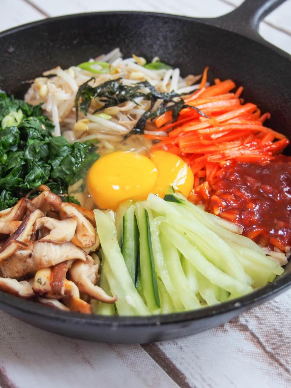 vegetarian bibimbap as dolsot bibimbap in skillet with raw egg in middle