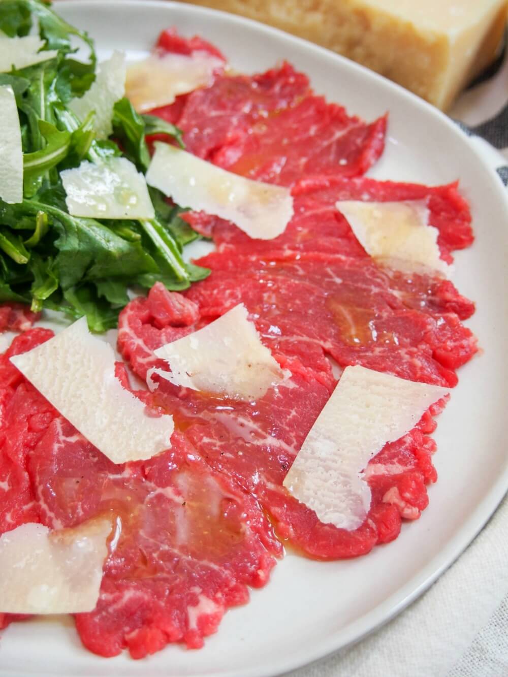 close up of beef carpaccio showing glint of dressing on top