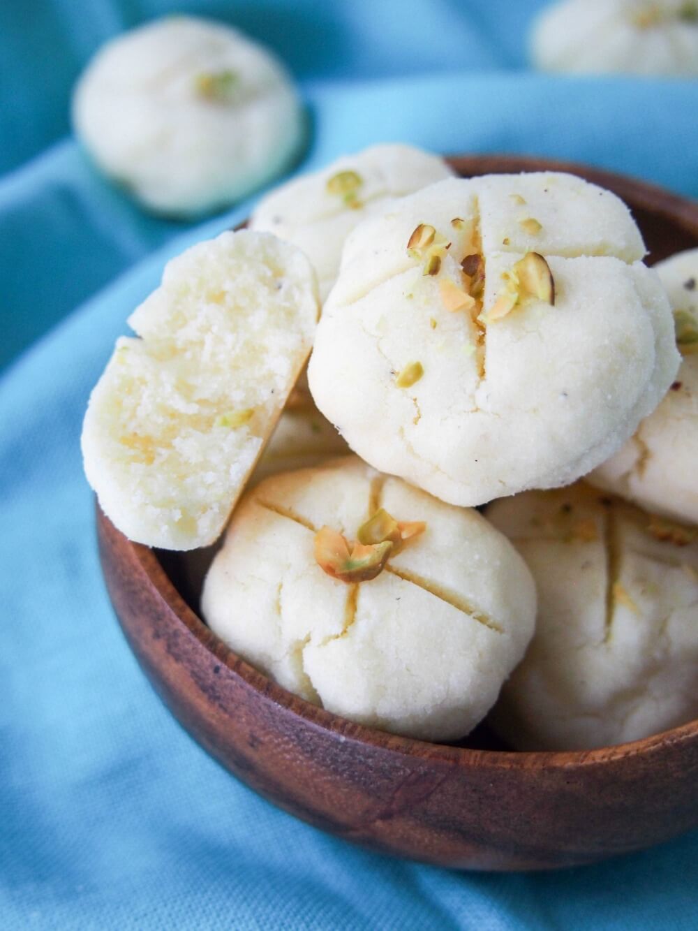 Persian rice cookies (nan-e berenji) close up in small bowl with one split open on side