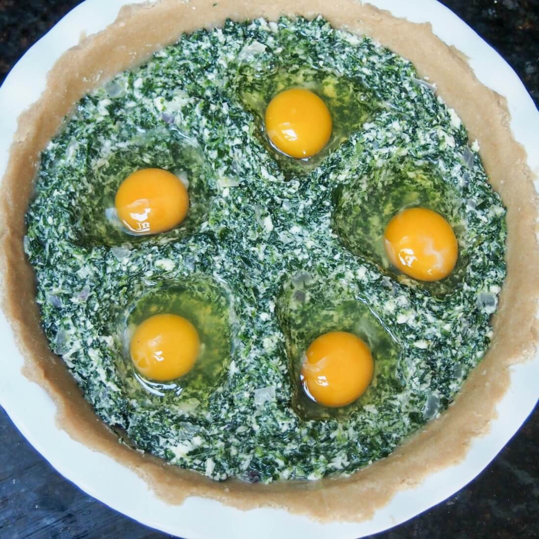 putting eggs in indents in spinach-ricotta filling