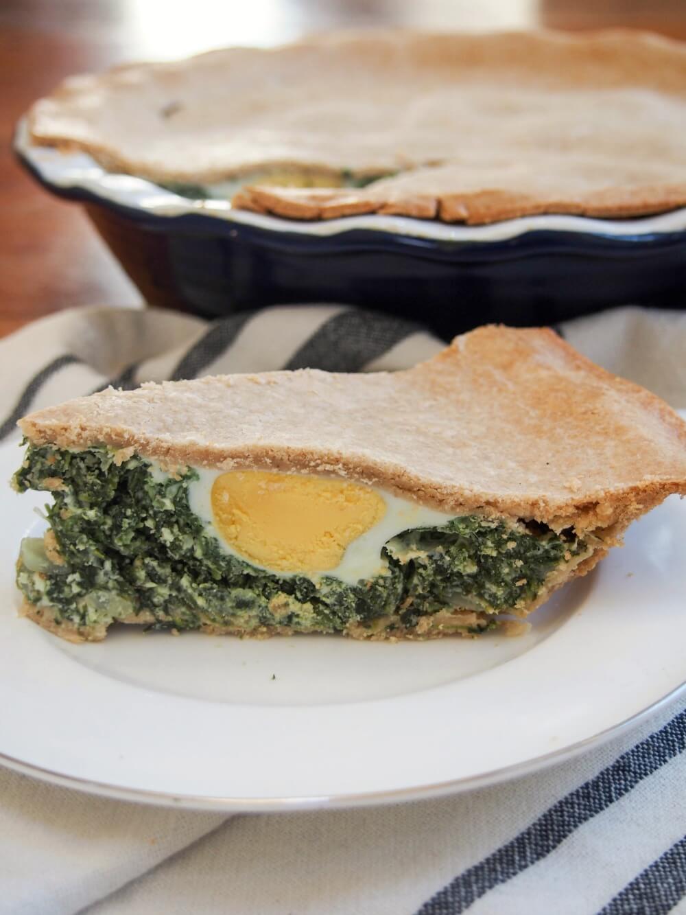 slice of torta pascualina spinach ricotta pie with egg showing in front of rest of pie