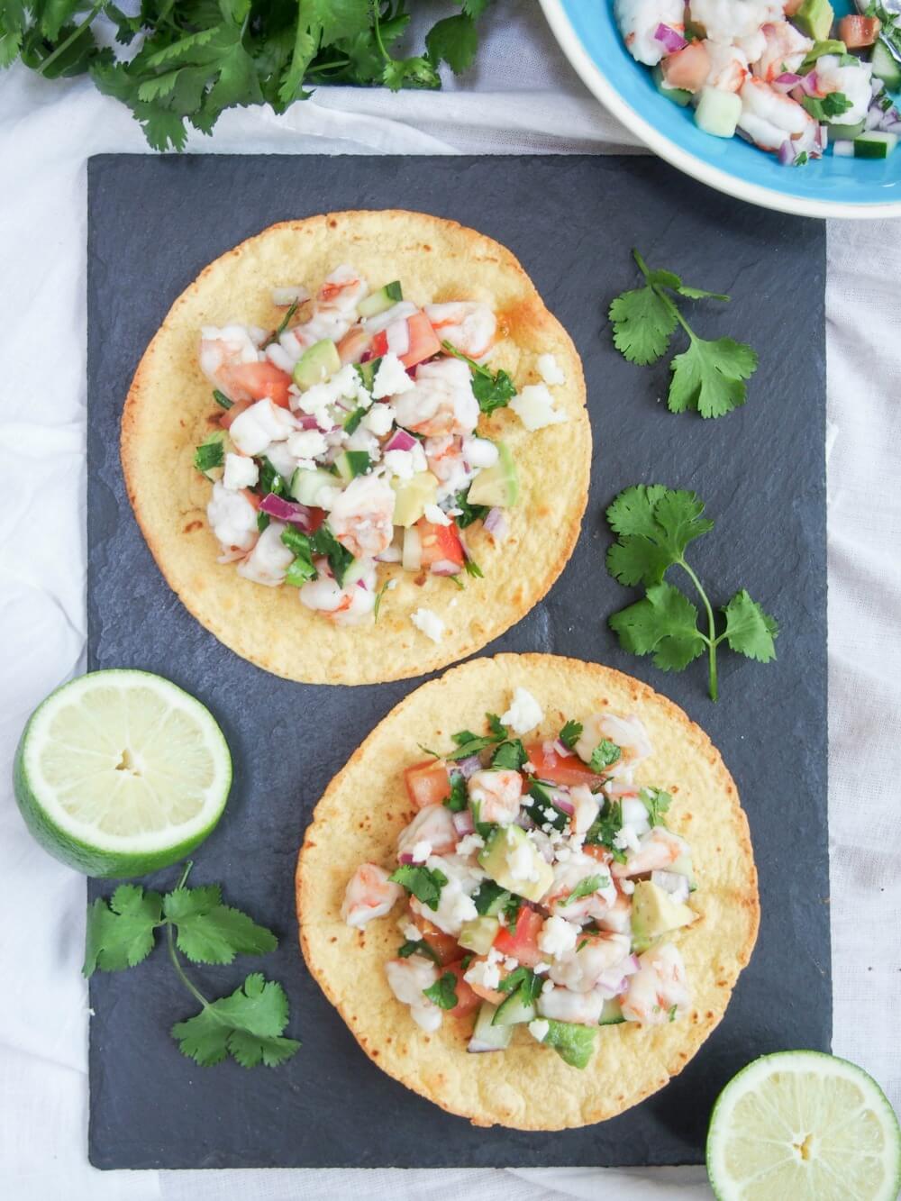 Shrimp ceviche tostadas on board from overhead with cut limes and cilantro to side