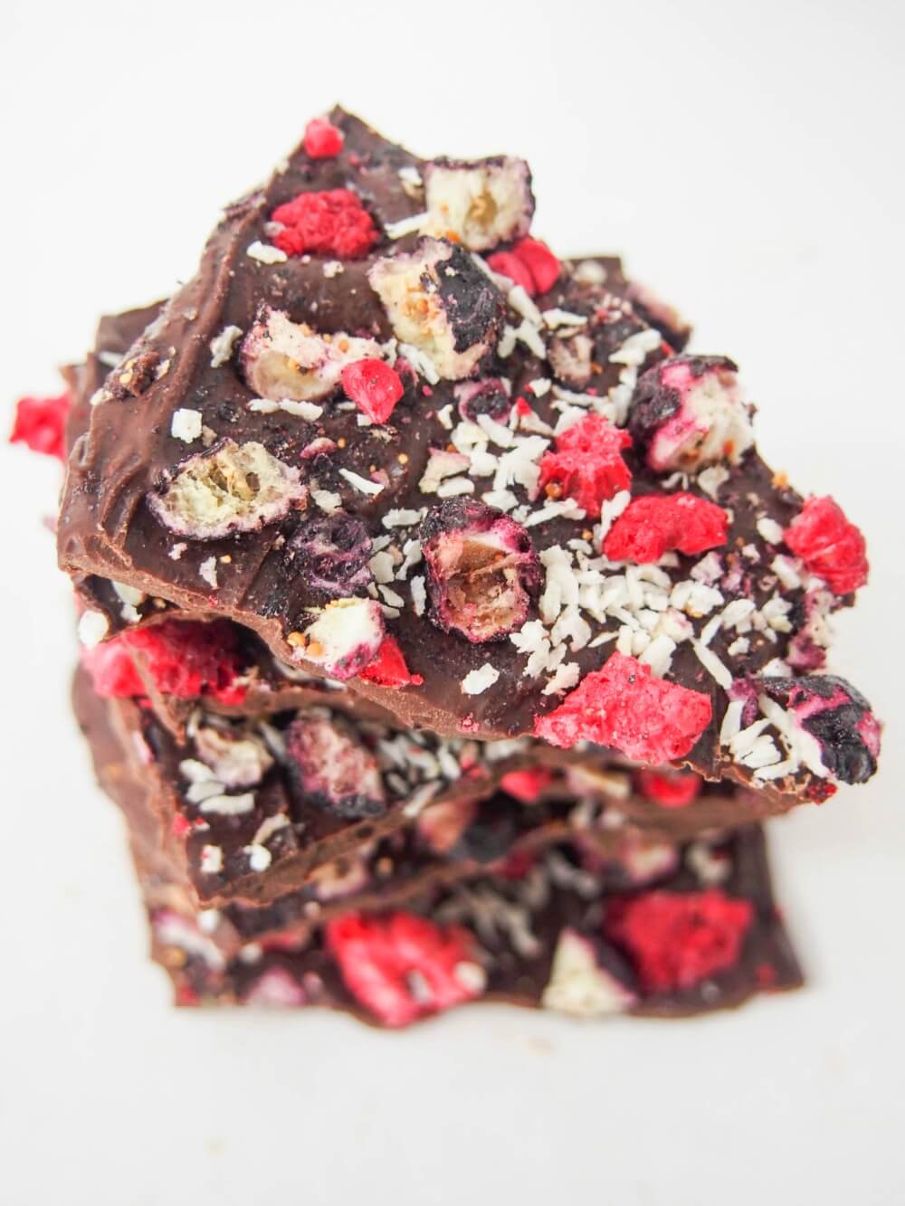 blueberry raspberry chocolate bark showing toppings on top piece in stack