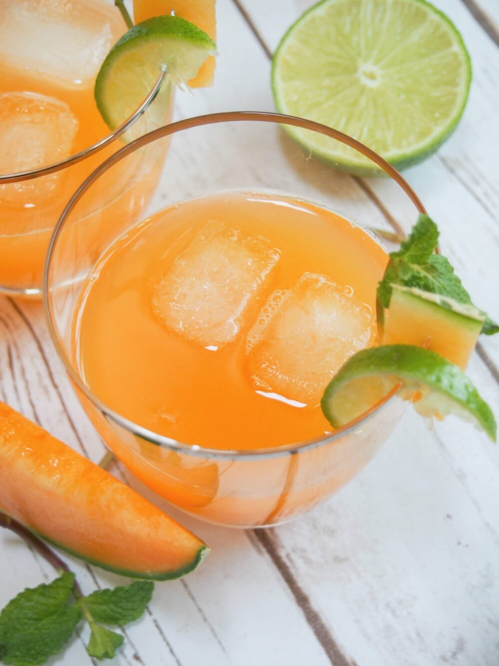 cantaloupe agua fresca with ice in glass and cut lime behind