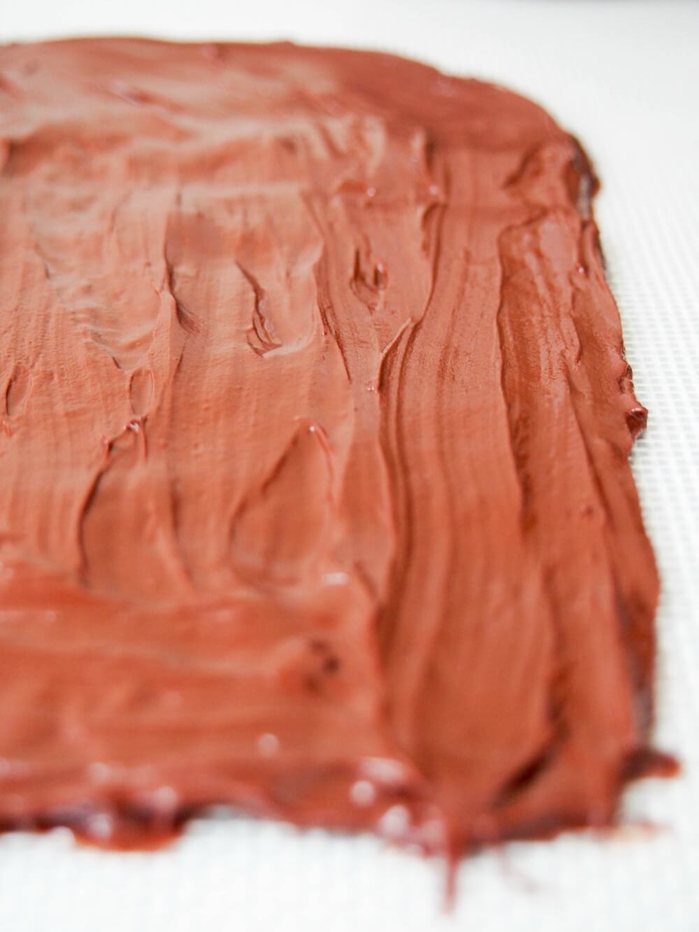 spreading melted chocolate in layer on silicone mat