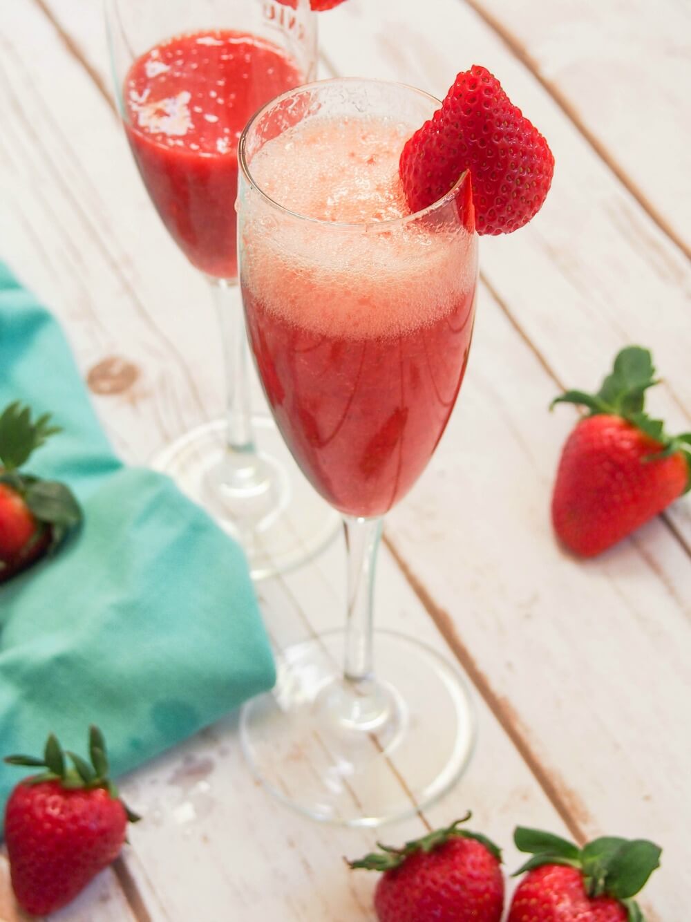 glass of strawberry bellini with bubbles on top and strawberry garnish on glass