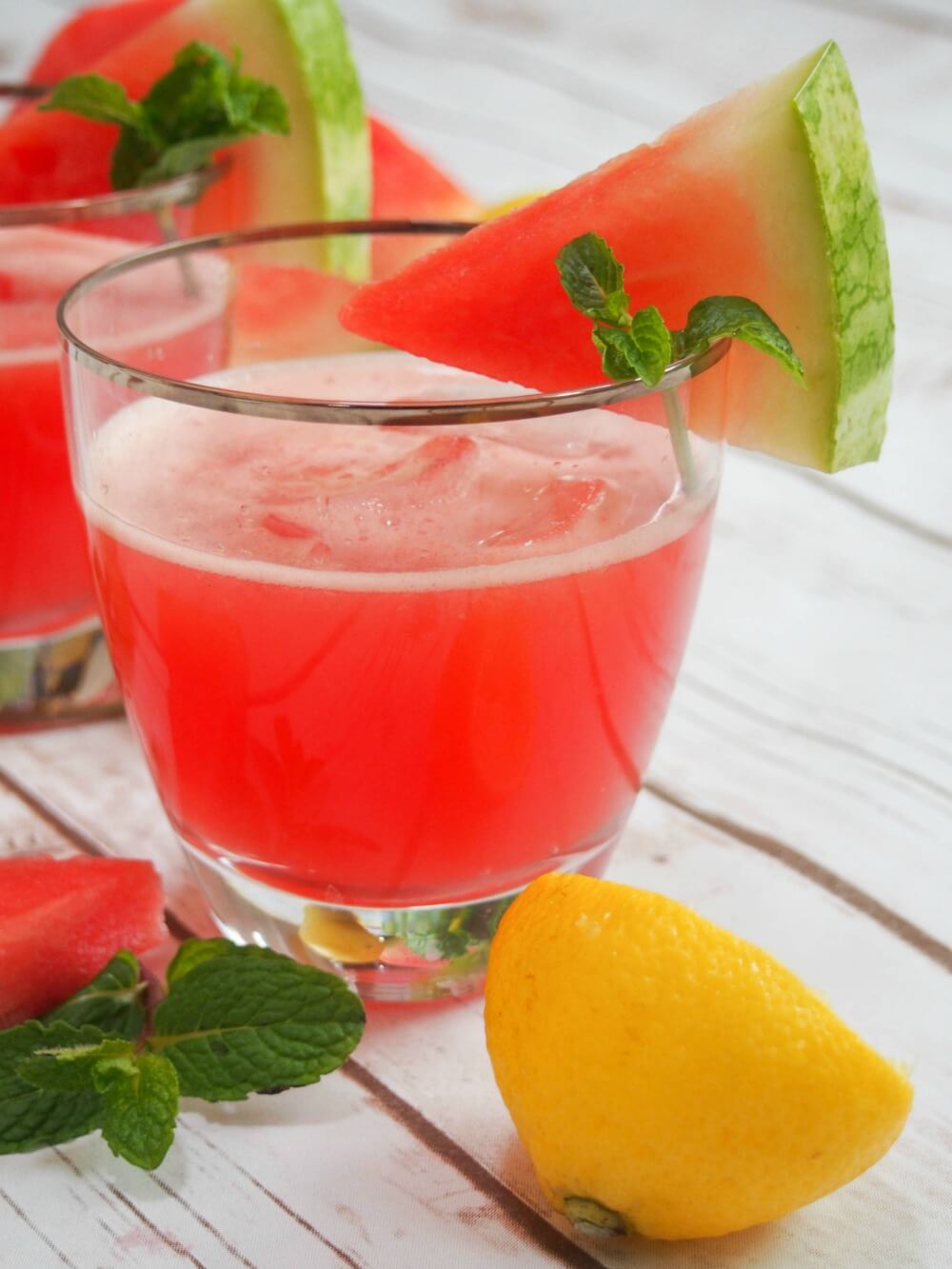 glass of watermelon lemonade viewed from side with watermelon chunk garnish