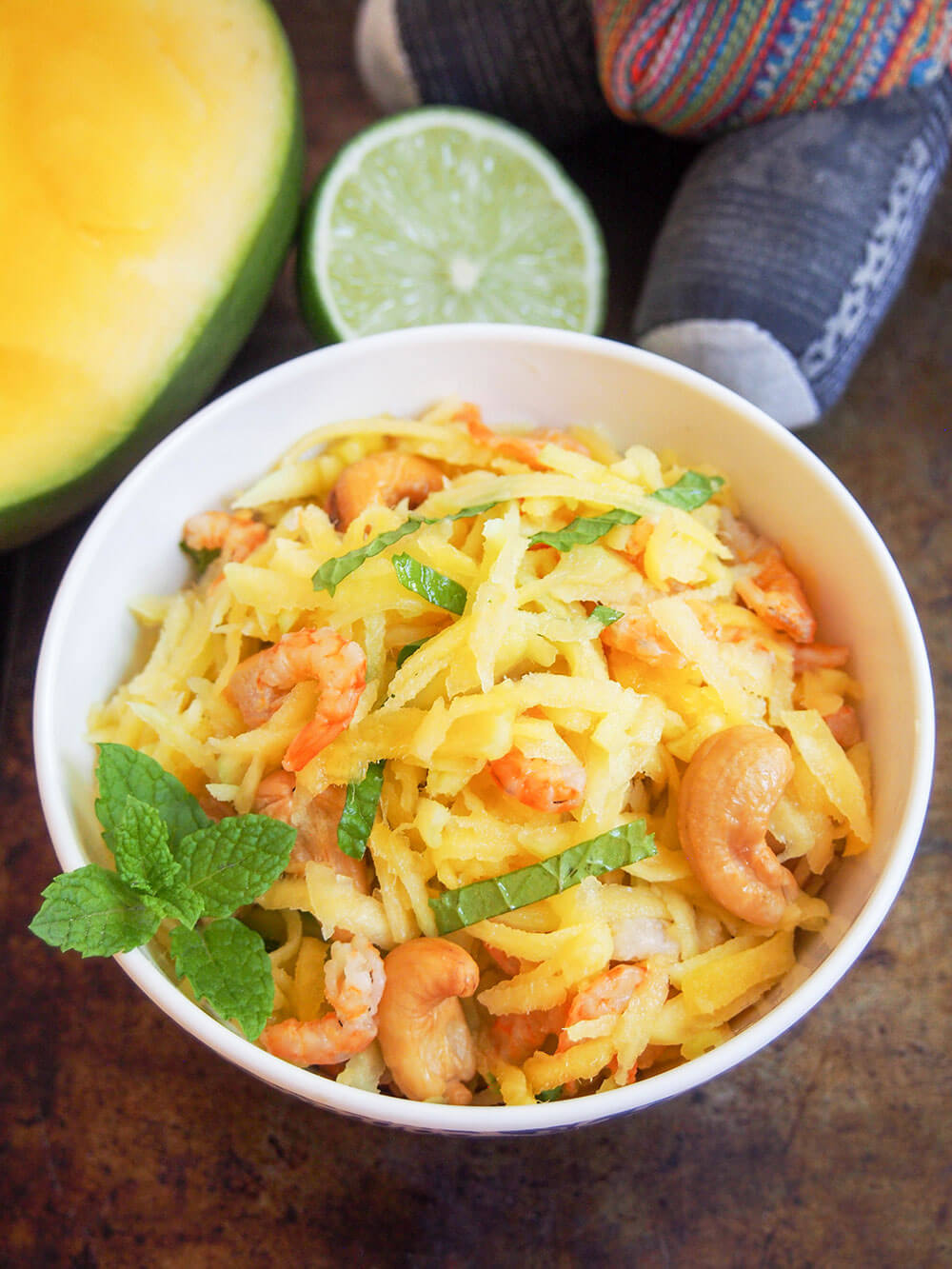 This Cambodian green mango salad is so easy to make and wonderfully fresh. Don't be put off by dried shrimp, they add a great flavor and texture to this simple, light side/appetizer perfect for summer. bowl of Cambodian green mango salad garnished with mint
