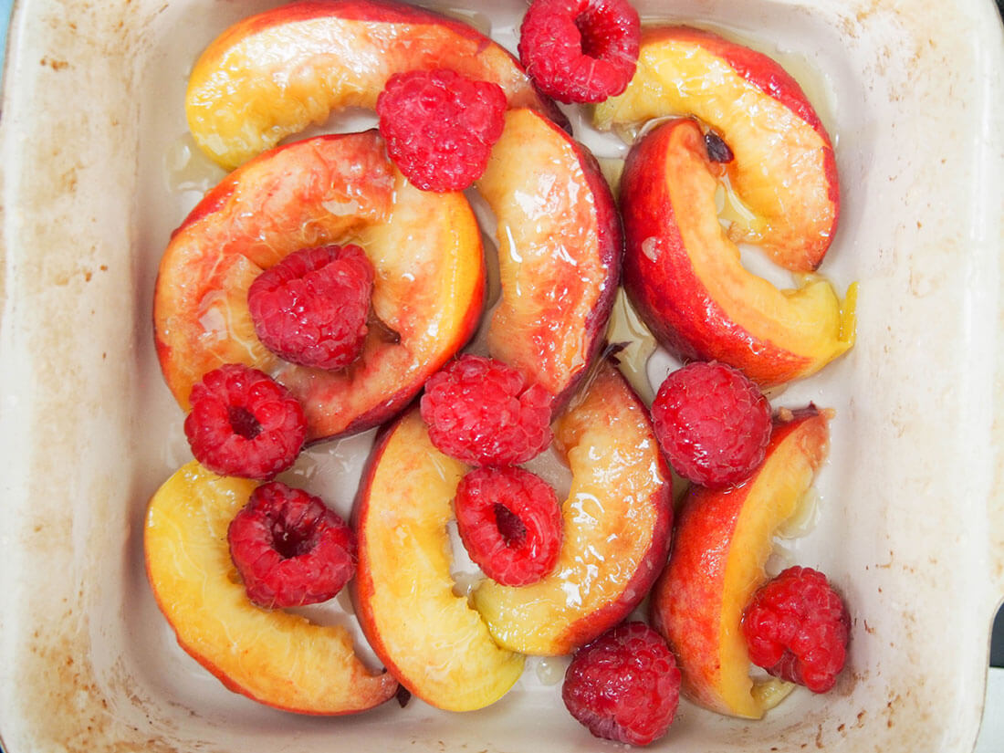 preparing fruit for peach Dutch baby pancake - peaches and raspberries ready to roast preparing fruit - peaches and raspberries ready to roast