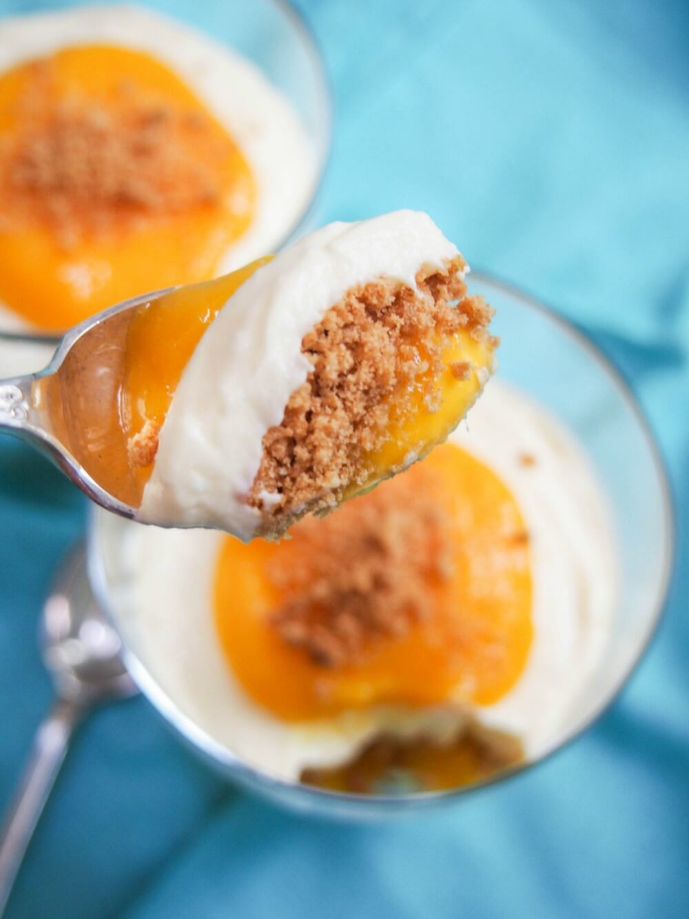 spoonful of mango cheesecake parfait held above glass