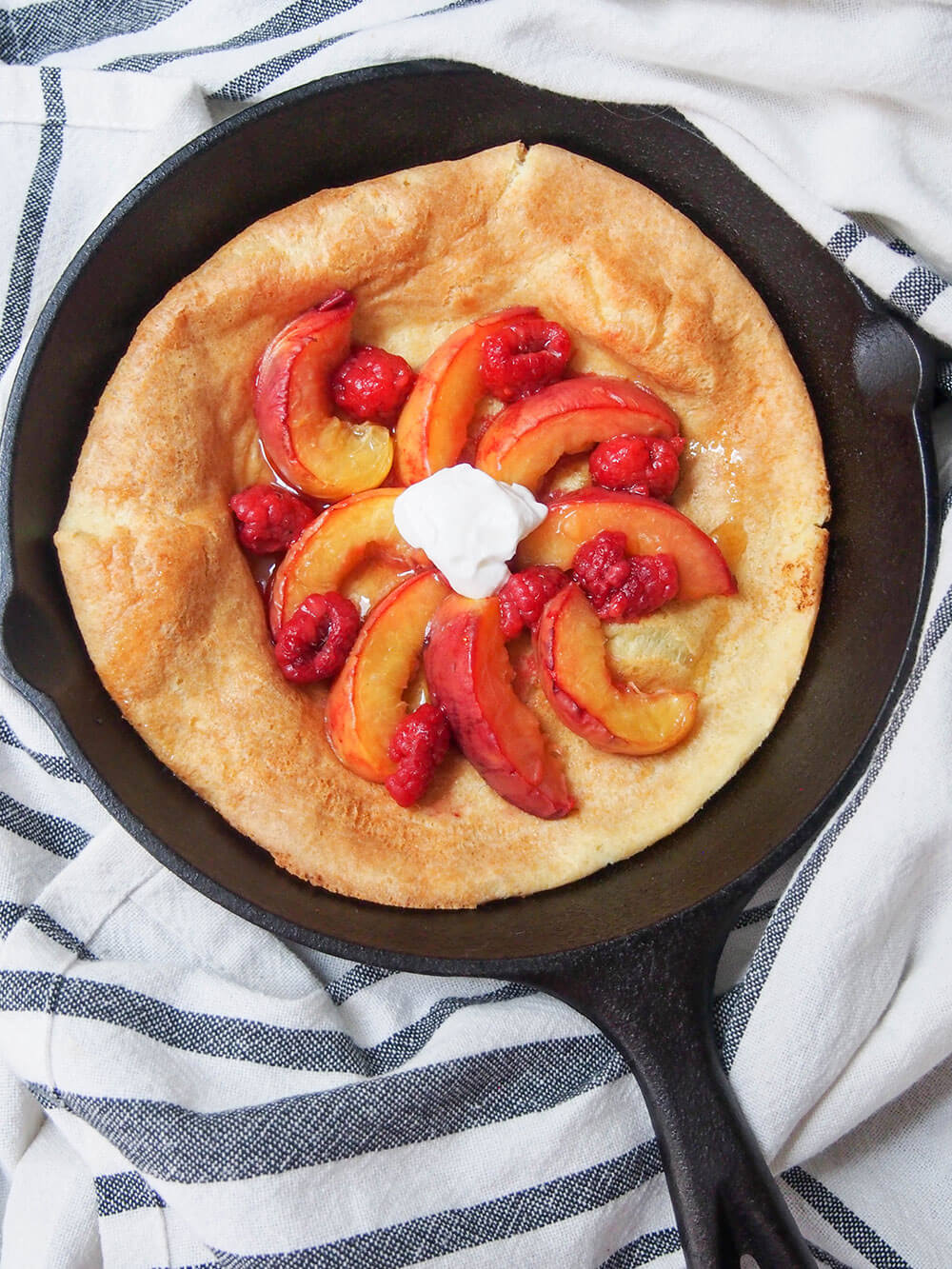 If you're looking for an easy breakfast/brunch that's packed with flavor, this peach Dutch baby pancake has to be high up the list. The roast peaches take this simple baked pancake from good to amazingly delicious! peach Dutch baby pancake in skillet from overhead