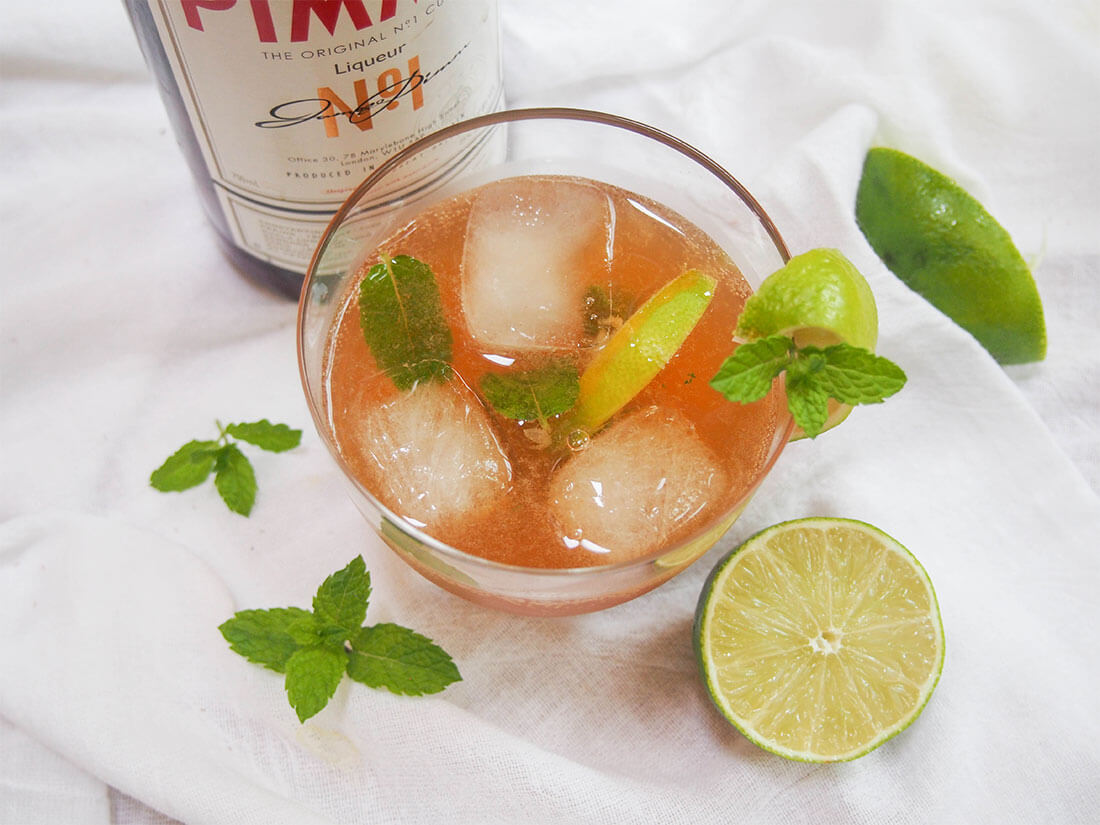 This Pimm's mojito is an alternative Pimm's cocktail that's just as refreshing as the classic Pimm's cup, and perfect for summer. So easy to make too. glass of pimm's mojito with lime to side and bottle behind