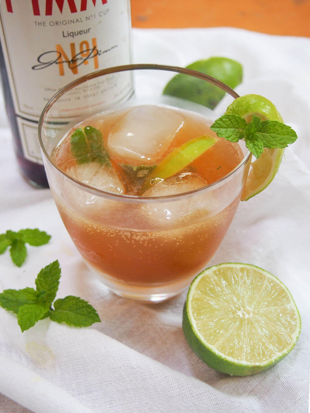 If you know of Pimm's at all, you probably know the classic way to serve it. But Pimm's is good for more than just one drink. This Pimm's mojito is an alternative Pimm's cocktail that's just as refreshing and perfect for summer. glass of pimm's mojito garnished with mint and lime slice showing bubbles on side of glass