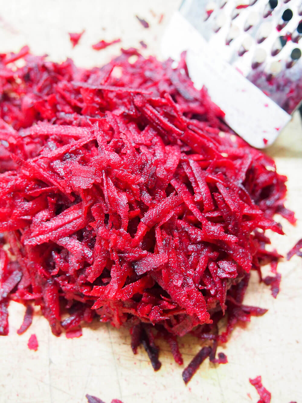 grated beets on chopping board with grater to side